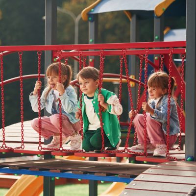One boy and two girls. Kids are having fun on the playground.