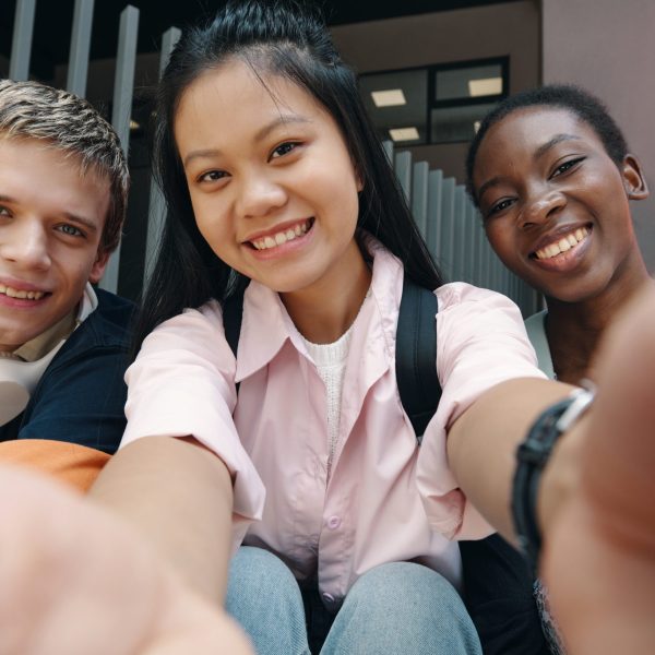 Happy girl making selfie portrait with her classmates outdoors